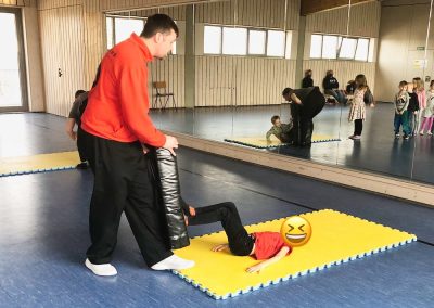 Der Trainer Marc Schulin erklärt einem Kind praktisch und spielerisch die Selbstverteidigung im Liegen